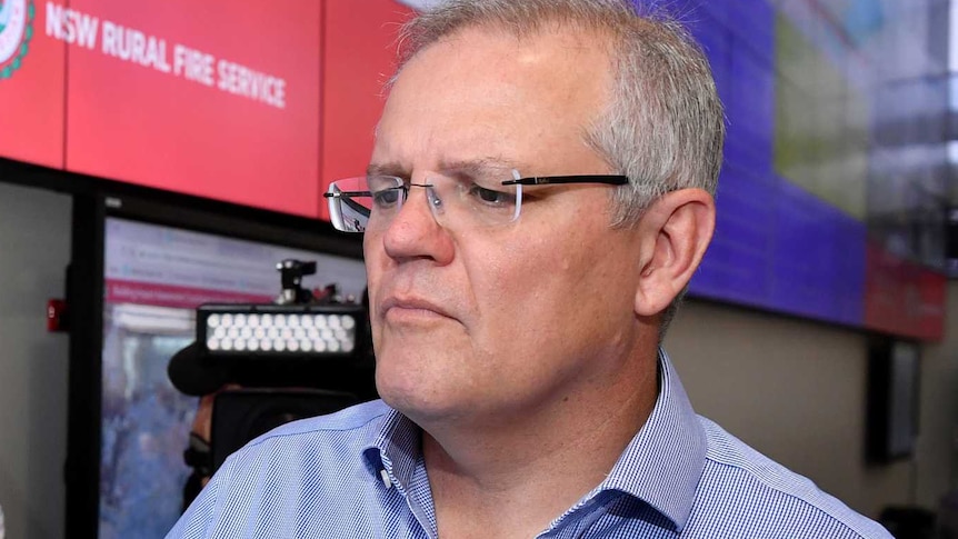 Scott Morrison looks at a screen at the RFS headquarters as a photographer and cameraman stand behind him