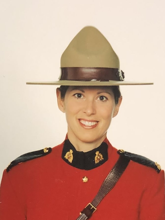 Head-and-shoulders photo of a smiling woman wearing the broad-brimmed hat and red jacket of the Royal Canadian Mounted Police.