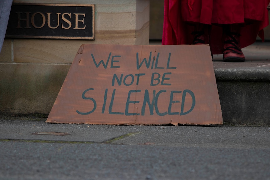 태즈메이니아 의회 밖에 있는 시위 현수막에는 “우리는 침묵하지 않을 것입니다.