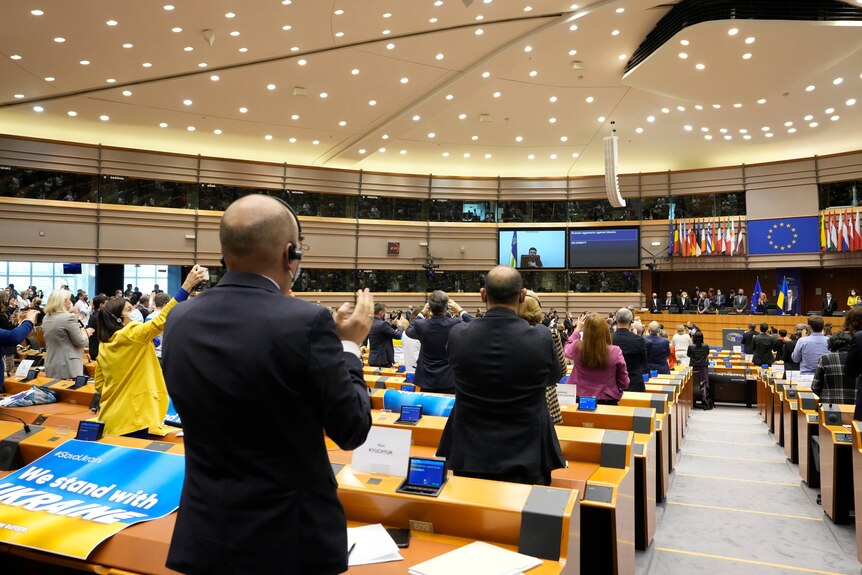 European Parliamentarians stand and applaud after an address by Mr Zelenskyy.