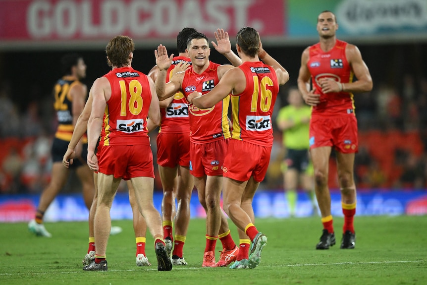 A group of Gold Coast Suns players celebrate after a goal.