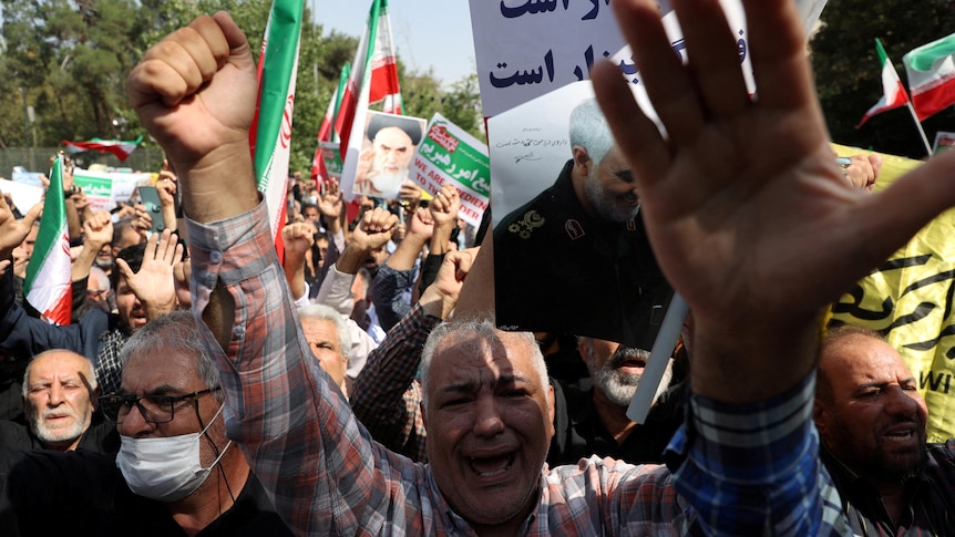 Demonstrators hold up Iranian flags and images of clerics.