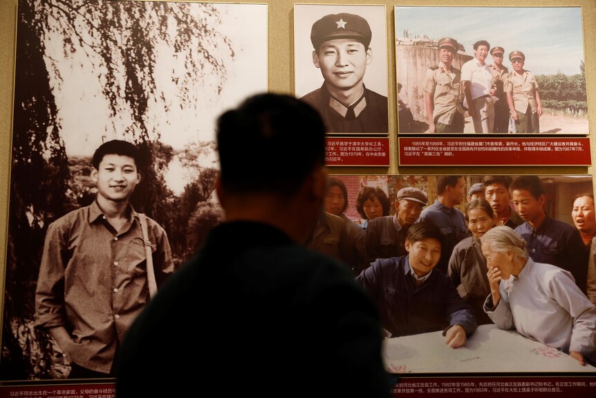 A man stands in the front of posters of China's national leader.