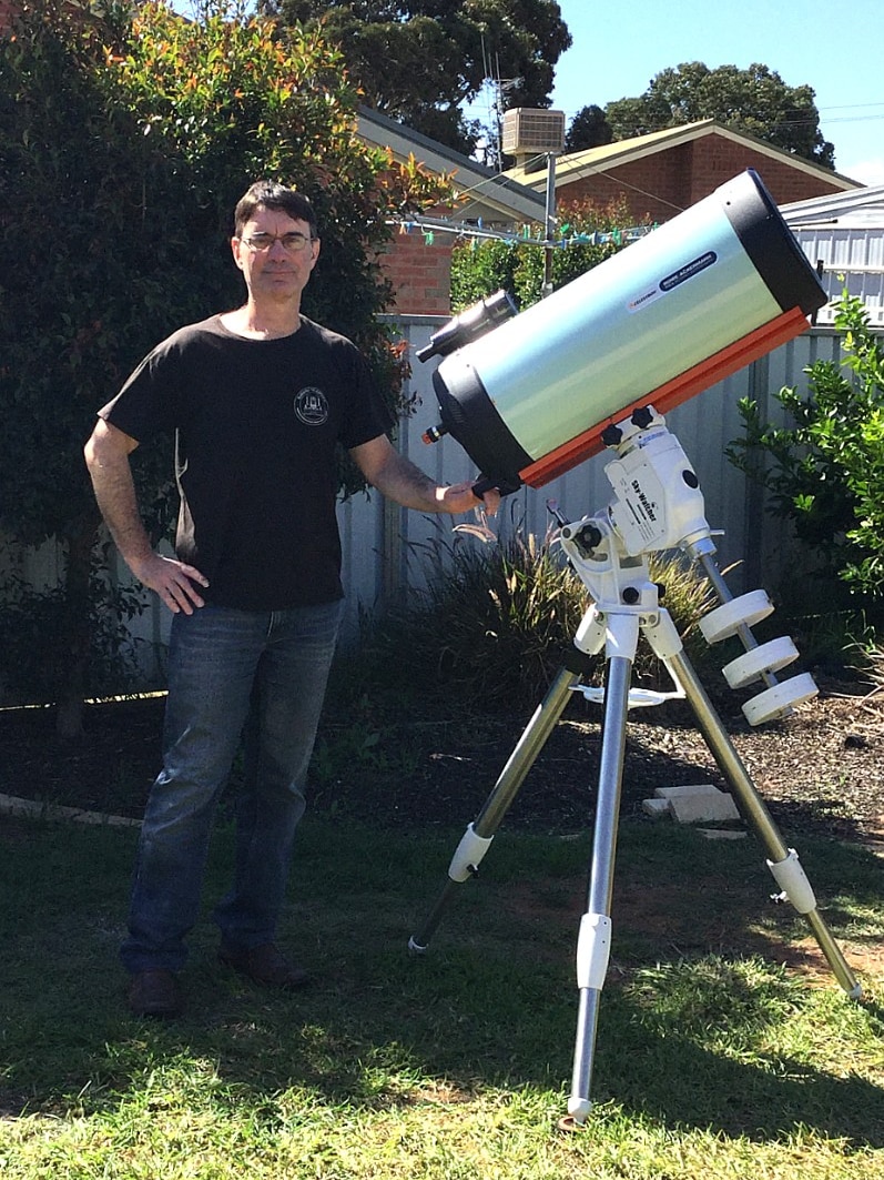 Michael Mattiazzo standing in his backyard with a large white telescope.