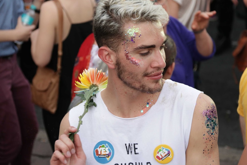 A man covered in glitter dances.