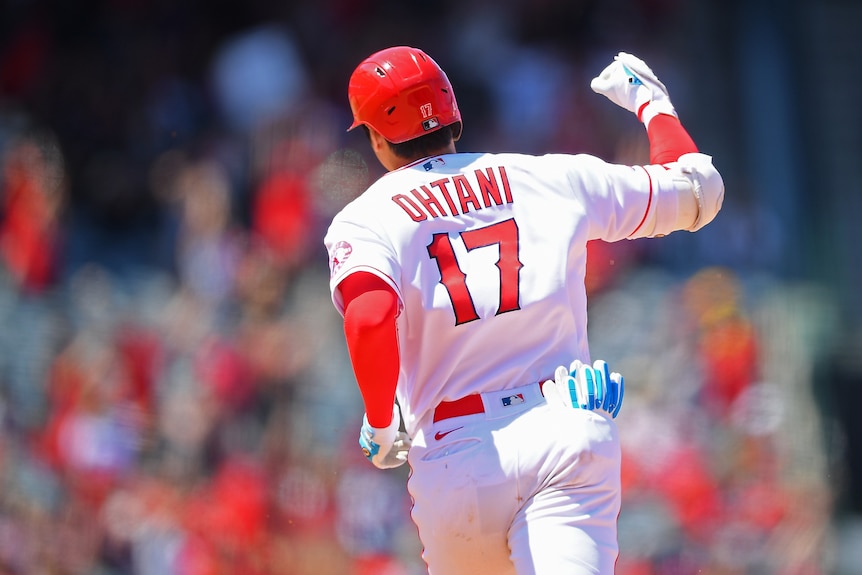 Shohei Ohtani rounding the bases in a white Angels jersey, pumping his fist.