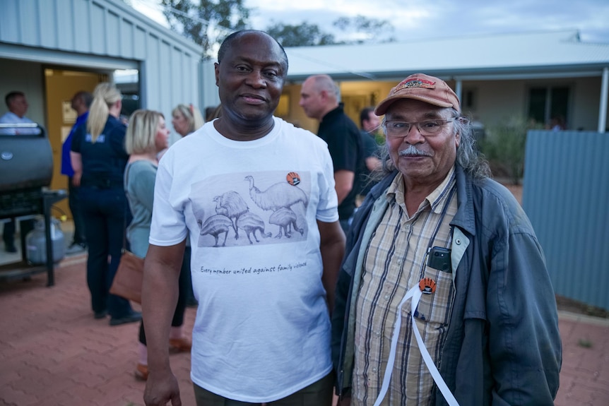 Two men stand side by side and smile at the camera