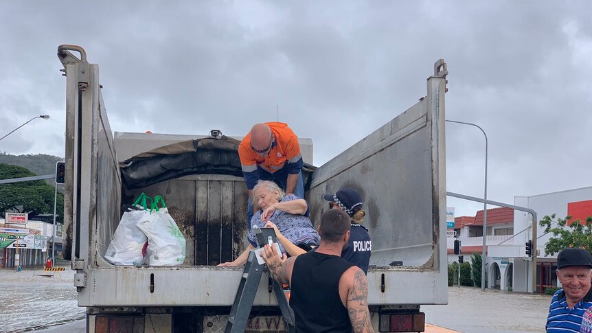 An elderly woman if helped on to the back of an empty truck during Townsville floods.