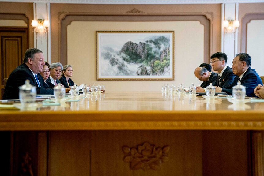Mike Pompeo and Kim Yong Chol speak sitting across a table from one another, with their delegations.