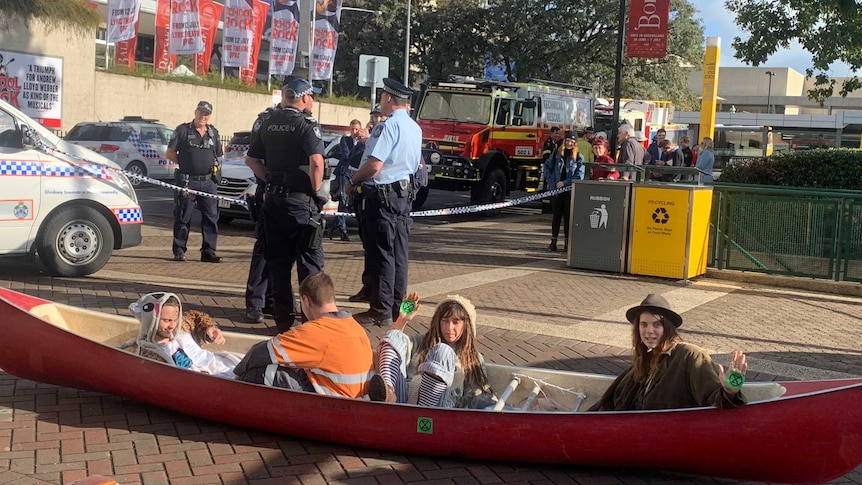 Protestors dressed in animal onsies sit on the road in a canoe.