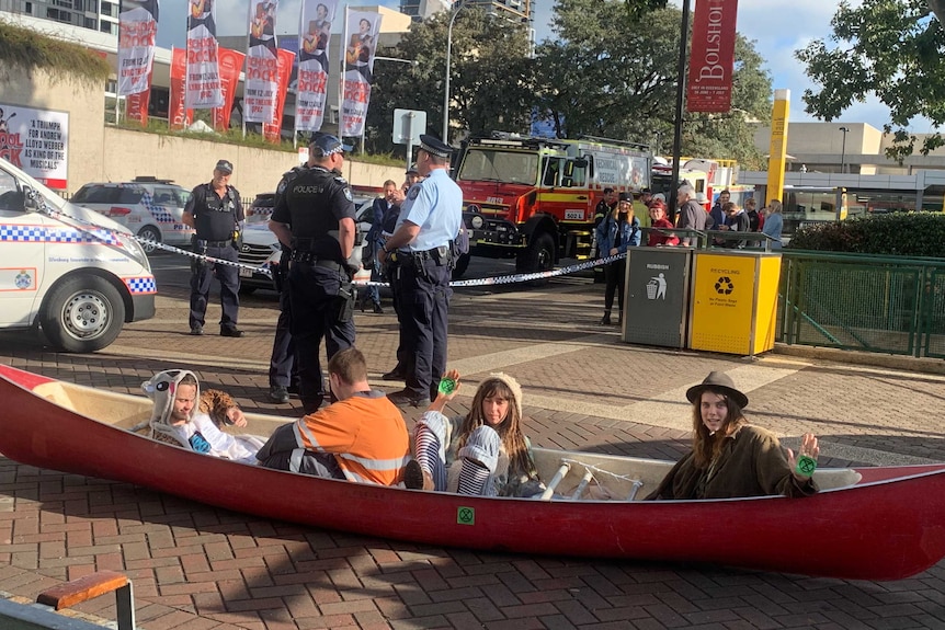 Protestors dressed in animal onsies sit on the road in a canoe.