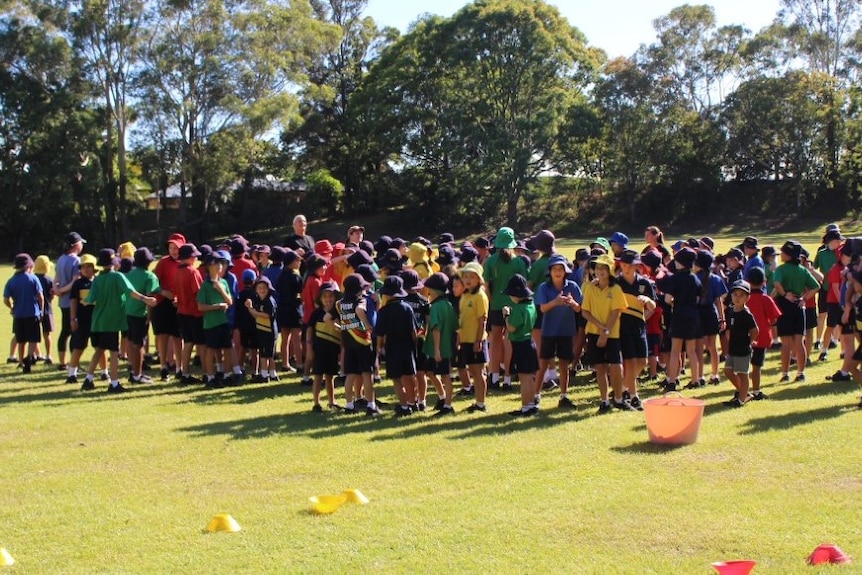 More than 100 students gathered around teacher on field