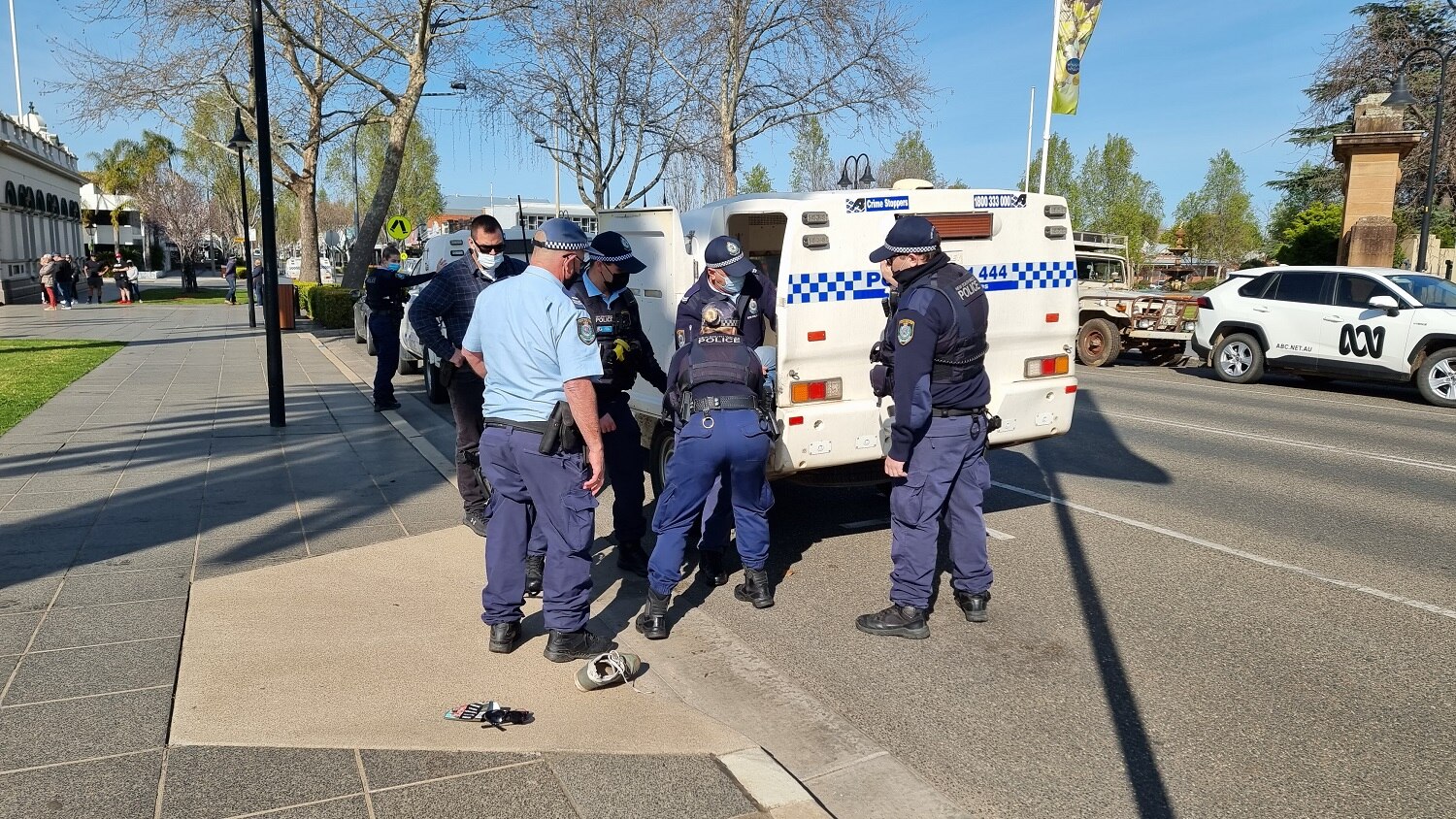 Multiple officers put a man inside a police vehicle.