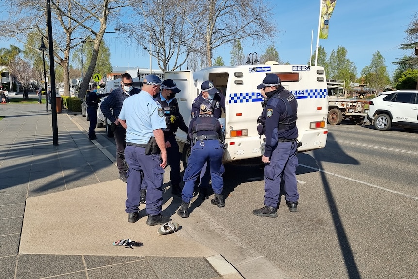 Multiple officers put a man inside a police vehicle.