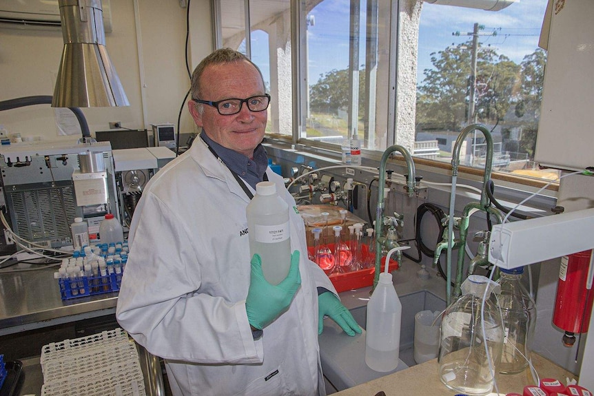 A man in a lab coat stands in a water testing facility