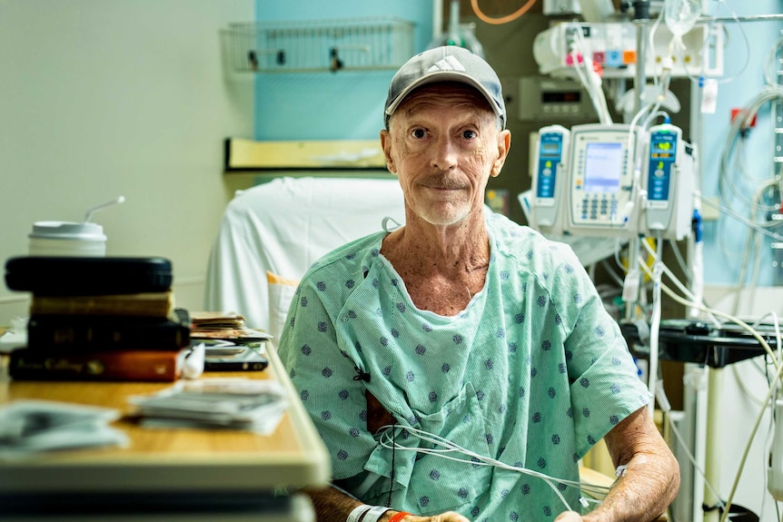 Ken Kasik, looking frail and weak, sits in a bed with medical machinery attached to his arms.