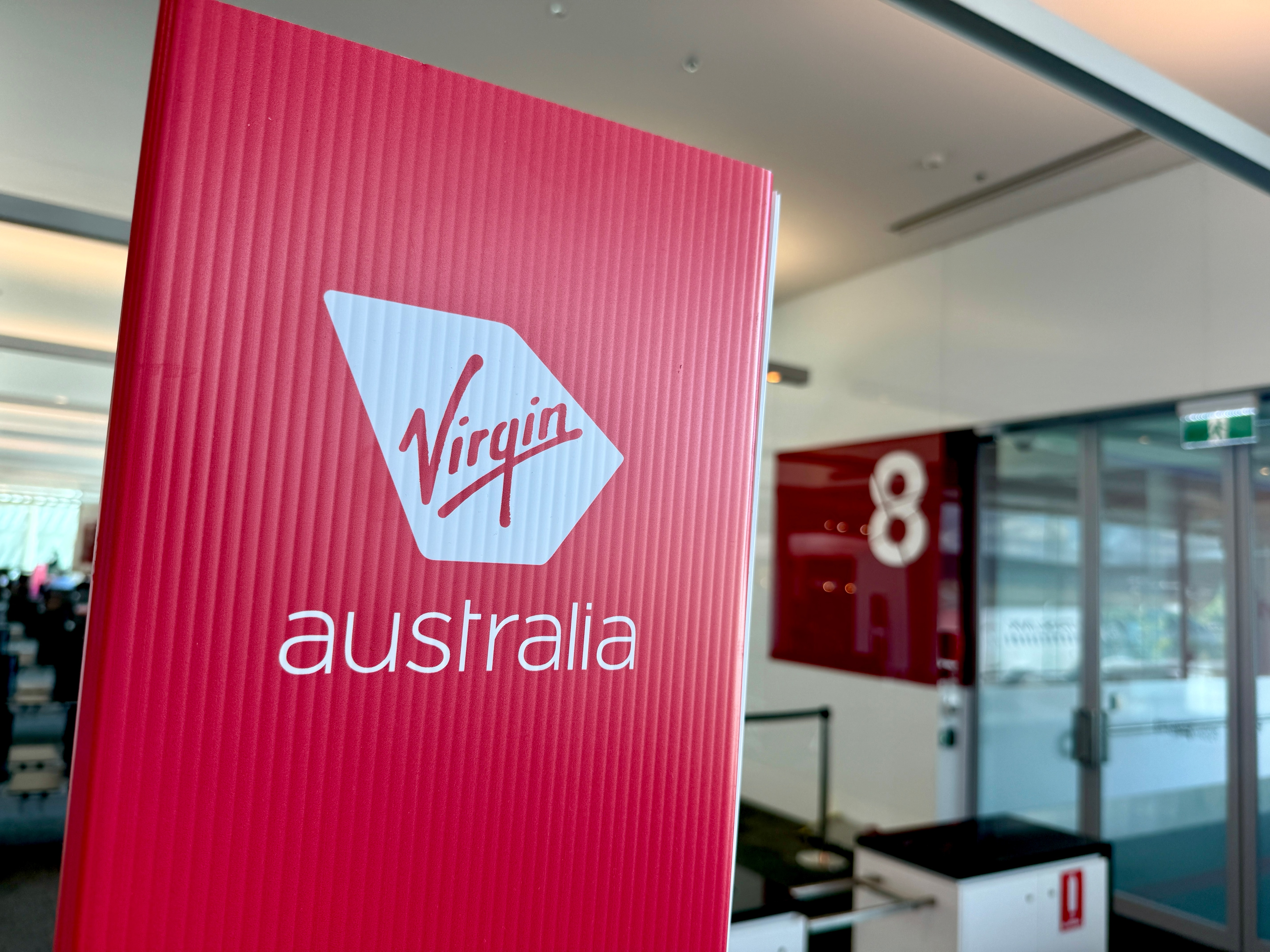 A red standing sign that reads "Virgin Australia" in an airport.