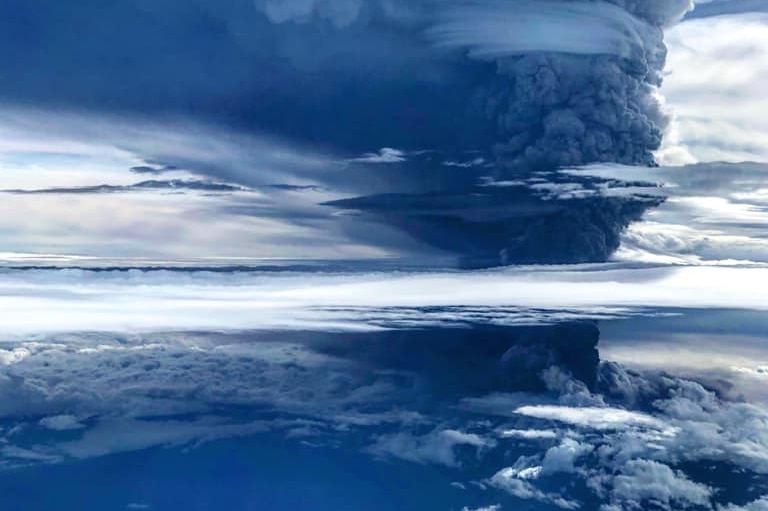 Smoke rising in a circular swirling motion in a deep blue sky.