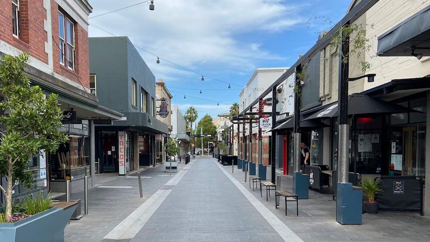 A deserted street in Geelong lined with closed food businesses on a sunny day.