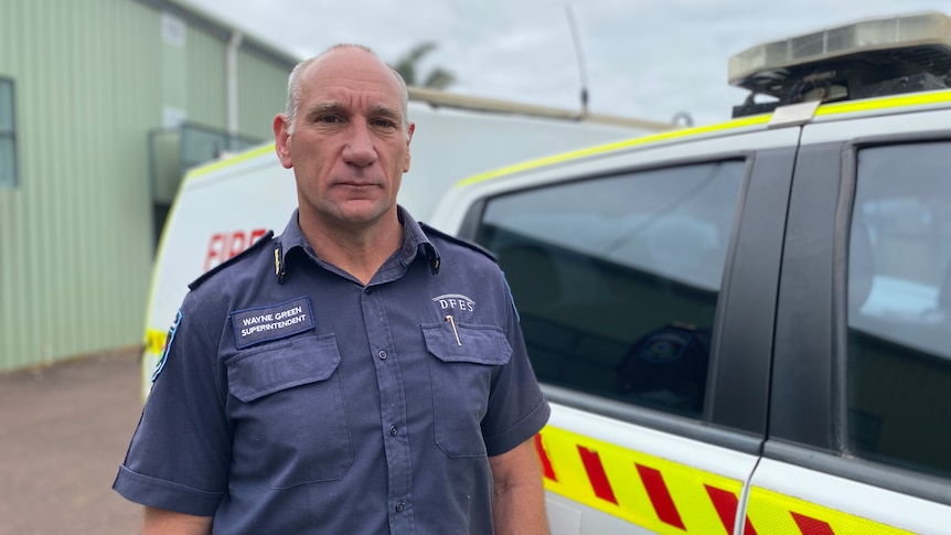 Wayne stands next to a fire emergency vehicle wearing blue DFES uniform