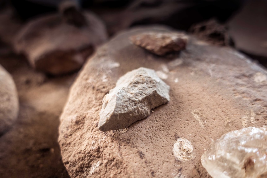 A rock shaped into a small spearhead sits on another larger rock.