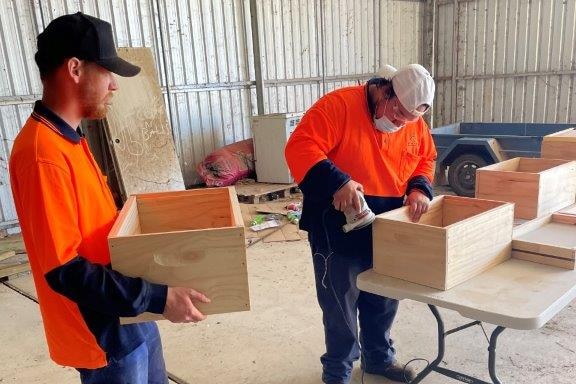 Two men work together to build bee boxes