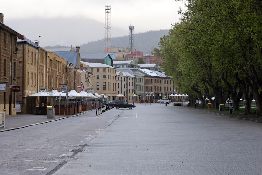 An empty street bordered by historic sandstone wharehouses 