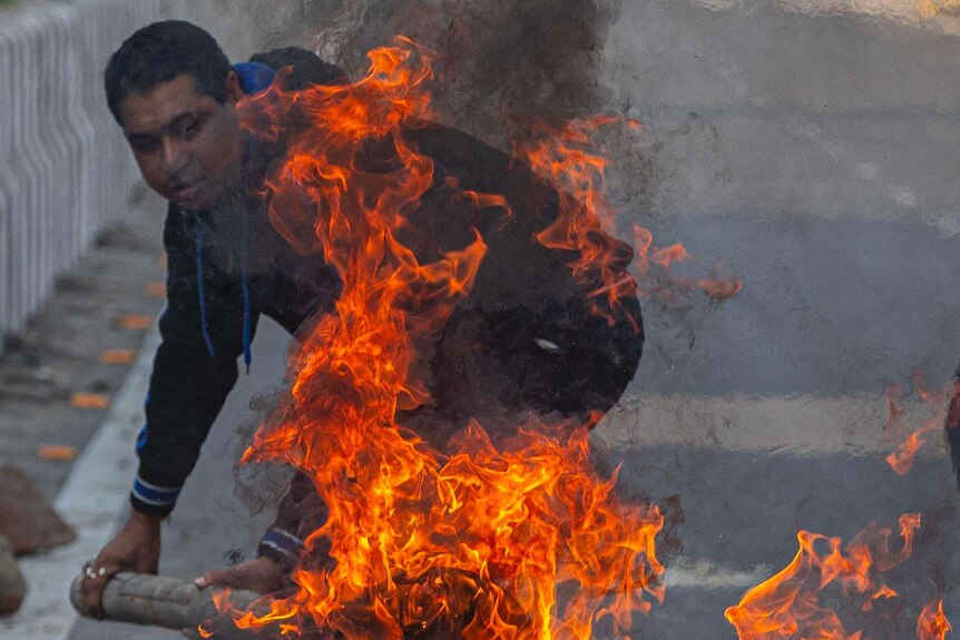 A protestor sets a fire in the middle of the road to block traffic in India.
