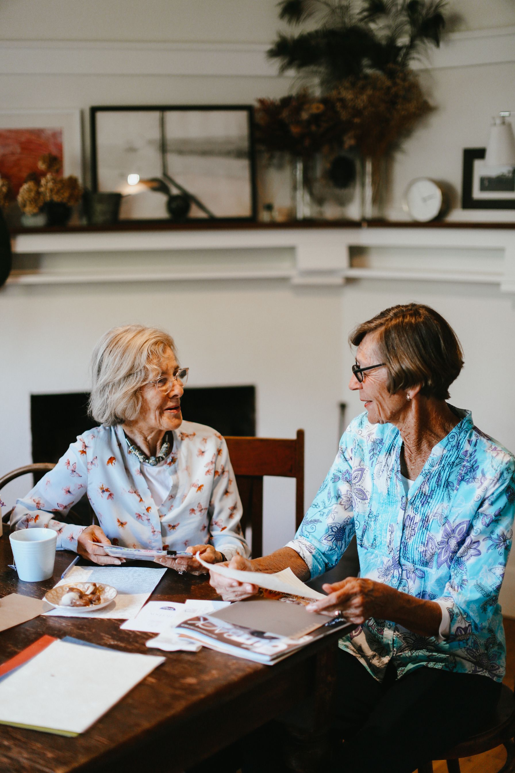 Two ladies sit reading mail and talking