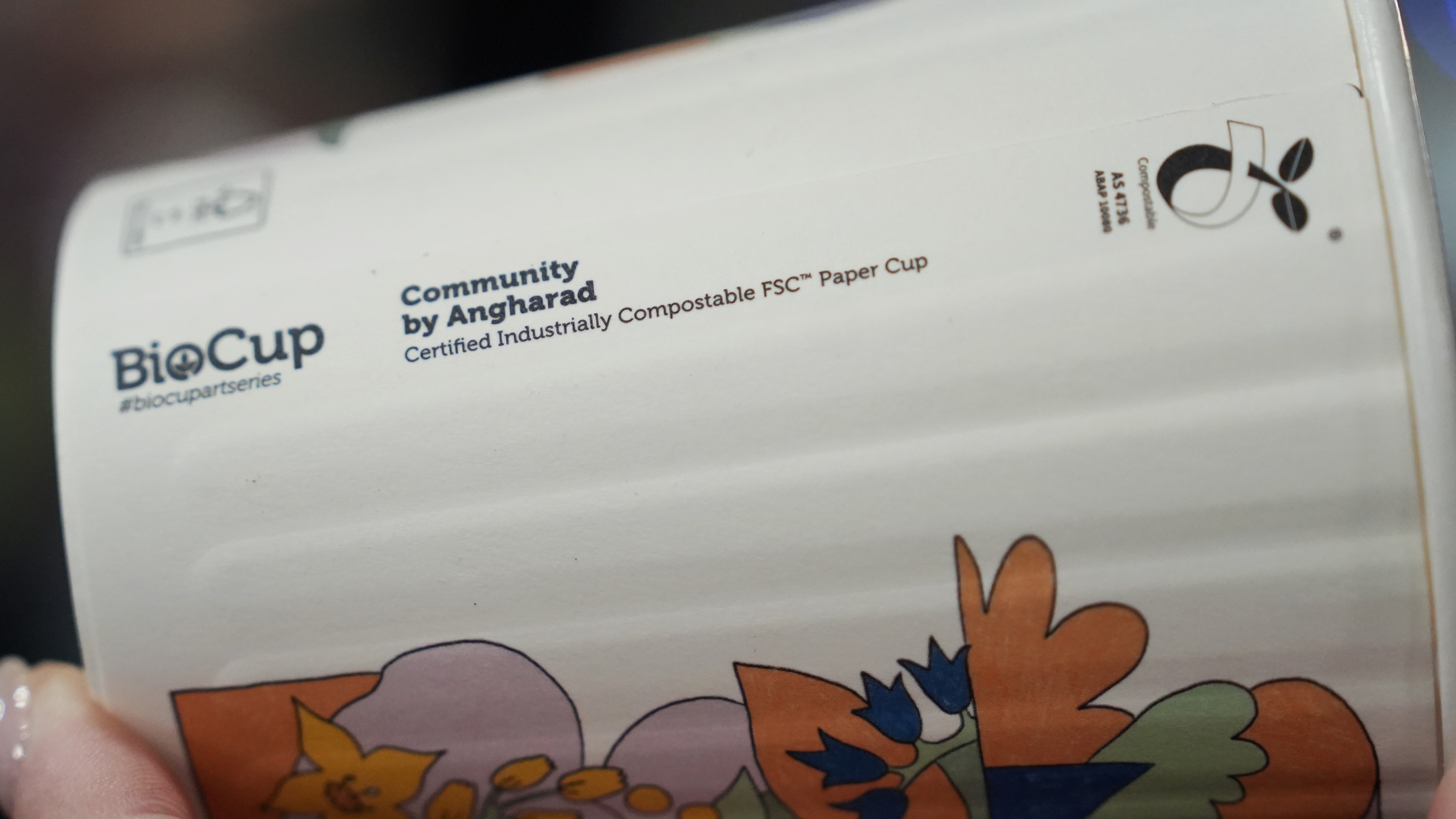 A paper coffee cup with the words "certified industrially compostable" printed on the side.
