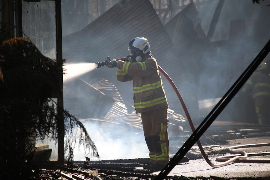 Firefighter sprays water on structure during the Rosebery bushfire emergency