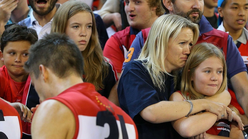 A Melbourne fan cries as Jack Grimes walks to the rooms after the 148-point loss to Essendon.