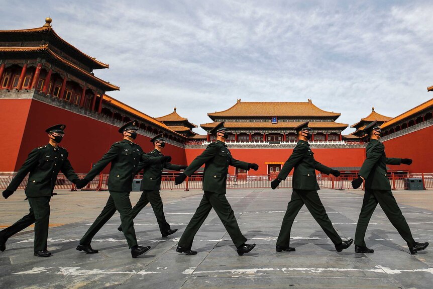 A group of Chinese soldiers in face masks march past the Forbidden City in Beijing