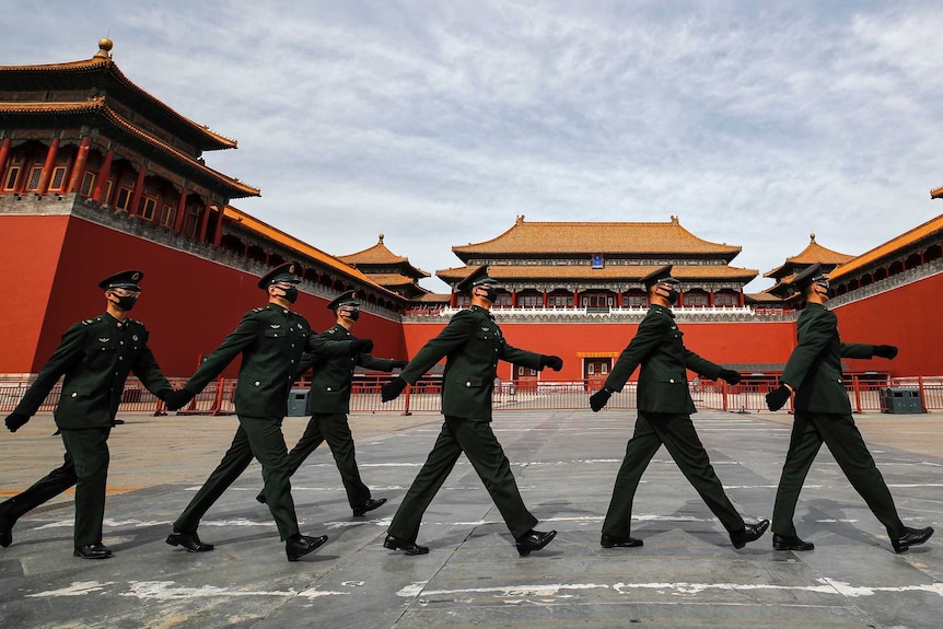 A group of Chinese soldiers in face masks march past the Forbidden City in Beijing