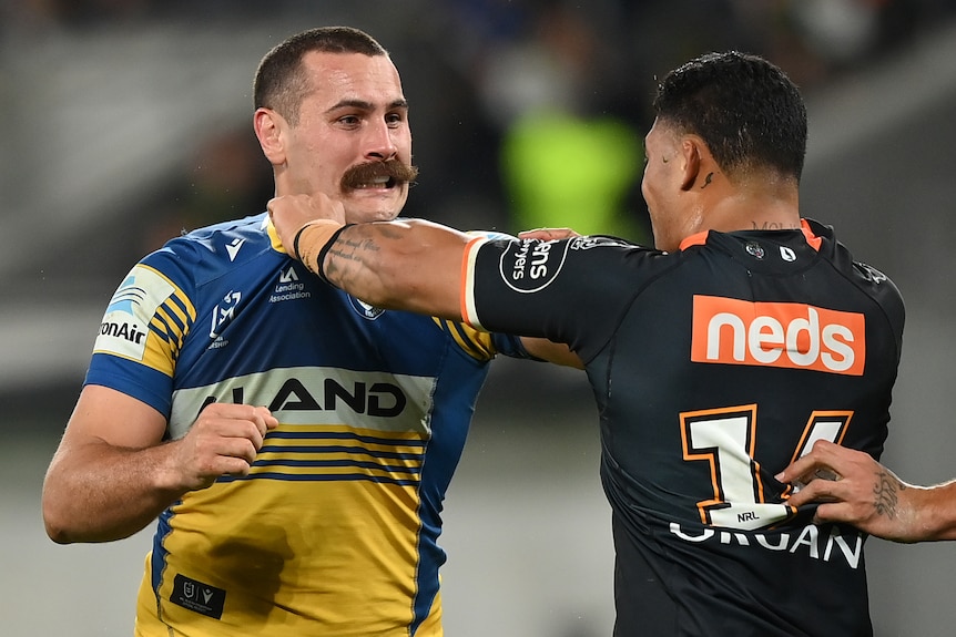 Parramatta's Reagan Campbell-Gillard grabs the jersey of Wests Tigers' Tom Amone, who is doing the same to Campbell-Gillard.
