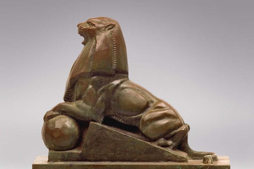 Art deco marble sculpture of a lion with its foot resting on a sphere