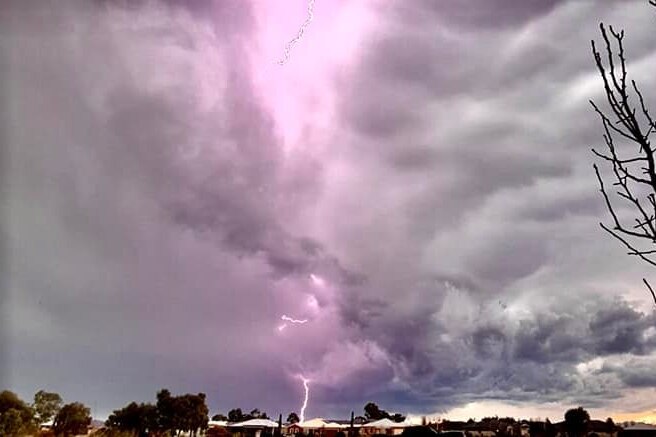 A fat bolt of hyper-coloured lightning spears earthward into a suburban area.