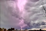 A fat bolt of hyper-coloured lightning spears earthward into a suburban area.