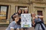 Schoolgirls hold a sign which reads: I've seen smarter cabinets at Ikea