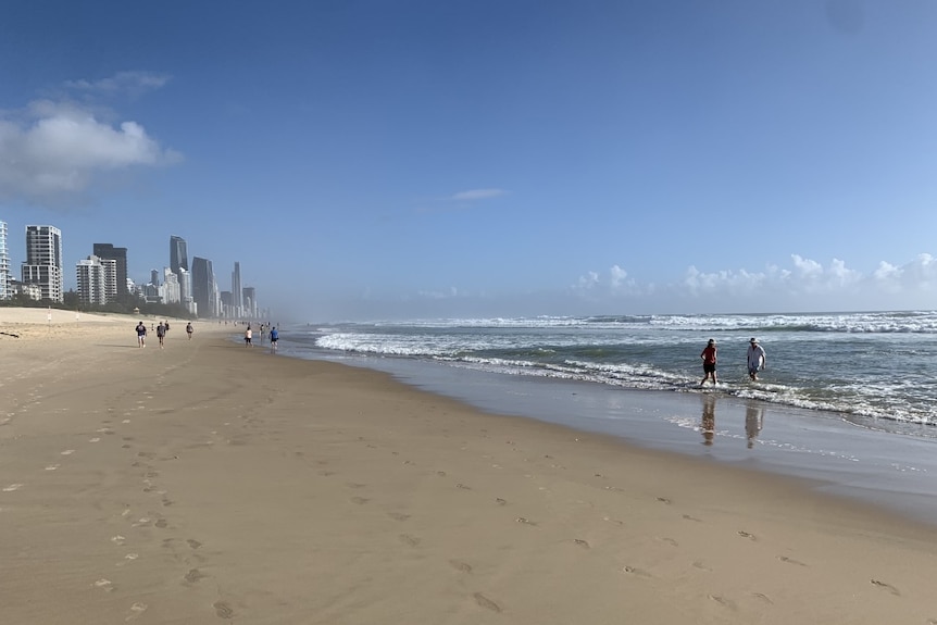 People walk along a beach.