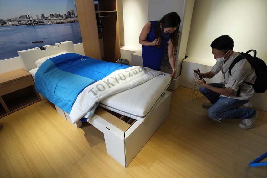 Journalists look at cardboard beds for the Tokyo 2020 Olympic and Paralympics