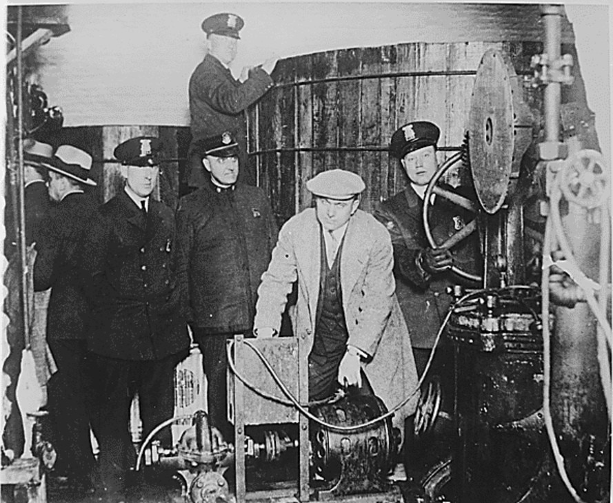 A black and white photo of Detroit police inspecting equipment during Prohibition.