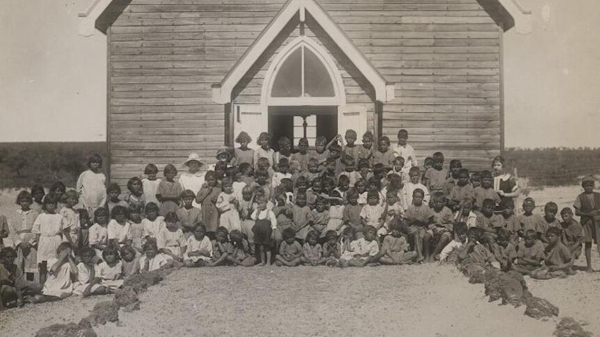 Old photo of large group of Aboriginal children sitting in front of church