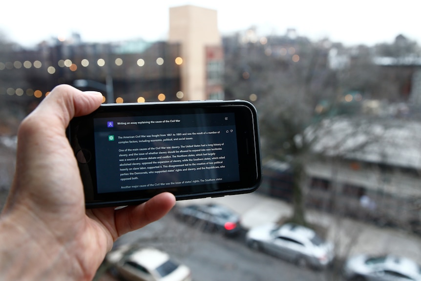A hand holds a phone showing the ChatGPT prompt in front of a NYC view. 