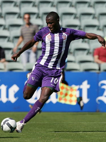 Million Butshiire wearing the Perth Glory colours in action coming up to kick a ball.