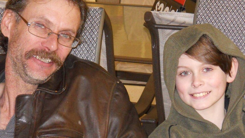 an older man and his son in a hoodie smiling at the camera