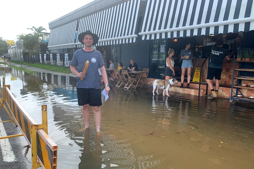 a man standing in ankle deep water, looking at the camera holding a large piece of bread