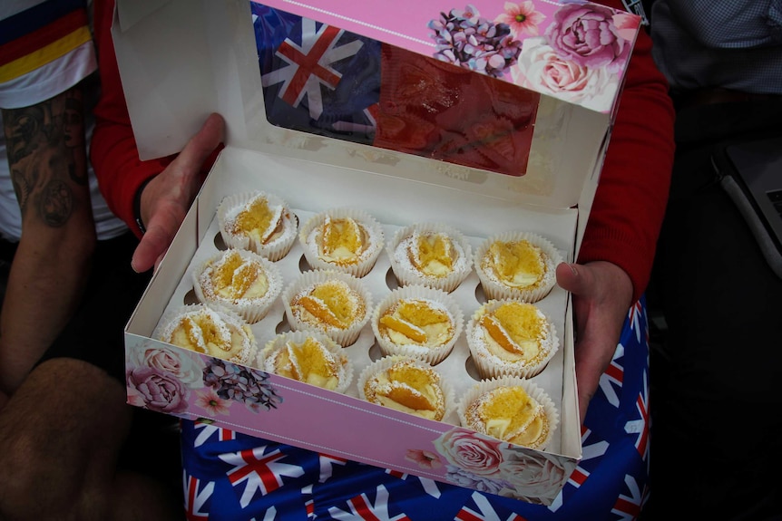 Kath Ryan clutching a cardboard box of butterfly cakes.