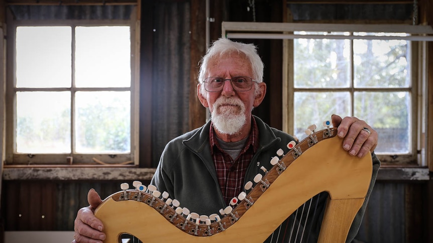 Geoff Welham stands behind a harp