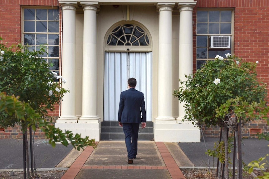 The new principal of Preston High School walks towards the school's entrance.